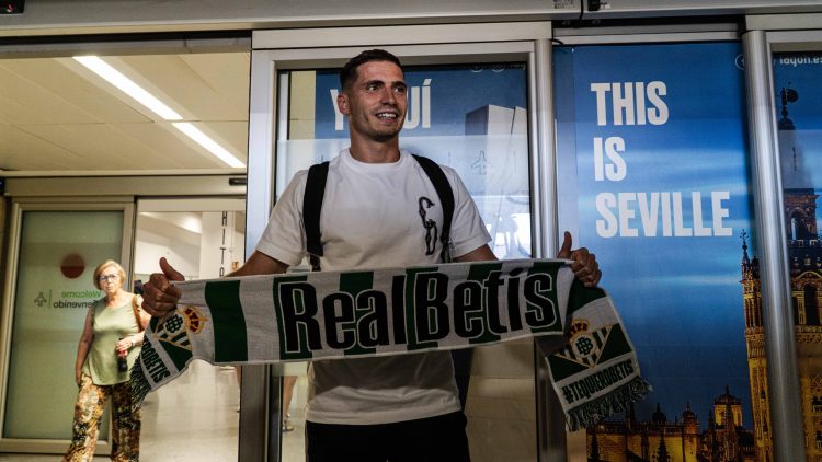 Romain Perraud en el aeropuerto de Sevilla posa con la bufanda de Real Betis | Imagen: Mario Míjenz -ZM