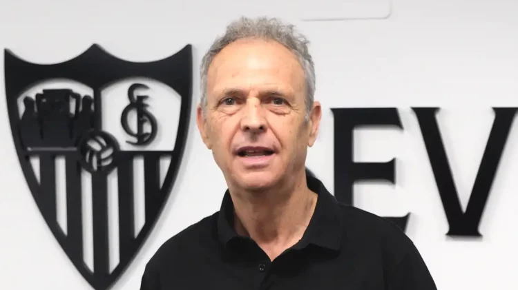 Joaquín Caparrós con el escudo del Sevilla detrás de él. | Imagen: Página web Sevilla FC.