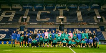 Plantilla del Real Betis posando sobre el césped del Cegeka Arena, estadio del Genk. | Imagen: perfil de X @RealBetis.