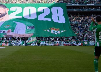 Isco con la lona que anunció su renovación con el Betis de fondo. | Imagen: perfil de X @RealBetis.
