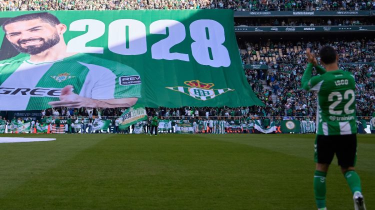 Isco con la lona que anunció su renovación con el Betis de fondo. | Imagen: perfil de X @RealBetis.
