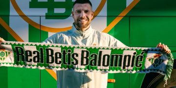 Aitor Ruibal posando con una bufanda del Betis. | Imagen: perfil de X @RealBetis.