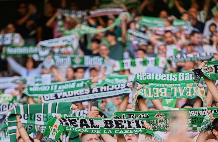 Aficionados del Real Betis desplegando sus bufandas. | Imagen: perfil de X @RealBetis.